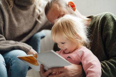 Daughter reading book with family at home