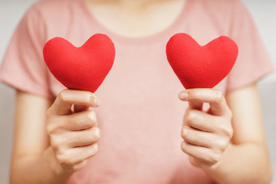 Midsection of woman holding red heart shape