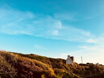 Panoramic view of a little house on the top of a mountain against trees against blue sky 