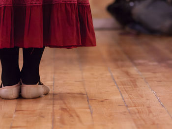 Rear view of a girl, standing on a wooden floor, during rehearsal