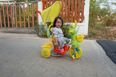 Portrait of cute girl sitting in tricycle on footpath