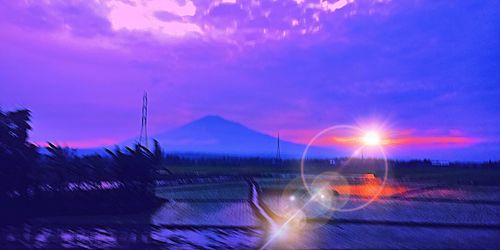 Panoramic view of illuminated field against sky at sunset