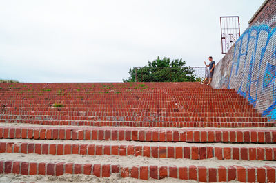 Man standing on steps by trees against sky