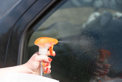 Woman washes the glass of car with a spray.