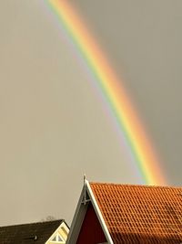 Low angle view of rainbow over building against sky