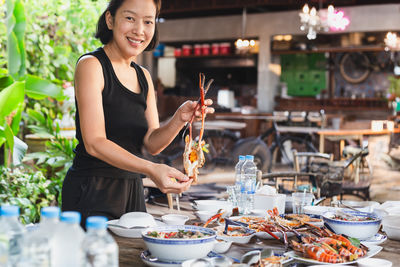 Happy asian women hold king prawn on outdoor table.