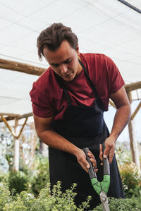 Young man looking away while standing against plants