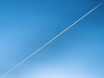 Low angle view of vapor trail against clear blue sky