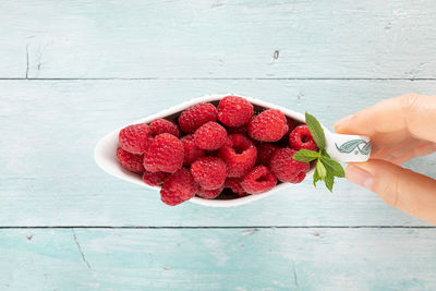 Directly above shot of hand holding strawberries on table