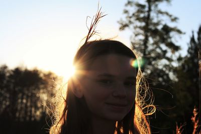 Close-up portrait of smiling young woman against sunset