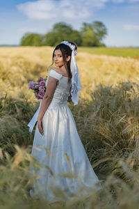 Young woman drinking water while standing on field