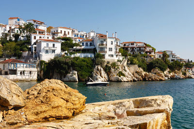 Buildings by sea against clear sky