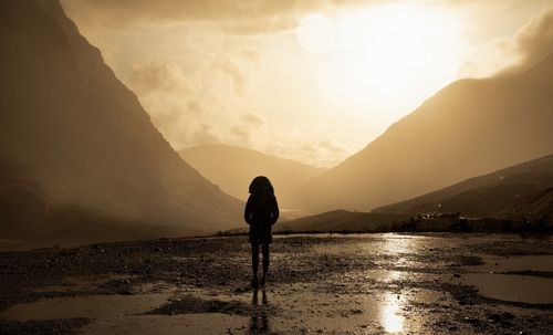 Woman standing against mountains during sunset