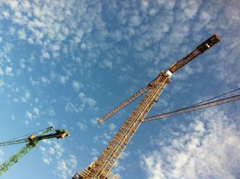 Low angle view of crane at construction site against sky