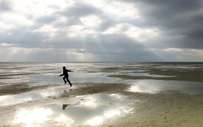 Silhouette man on beach against sky