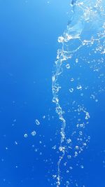 Close-up of water splashing against blue sky