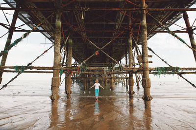 Rear view of girl standing under eastbourne pier