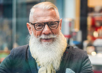 Portrait of bearded man wearing eyeglasses sitting in cafe