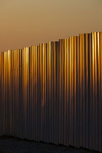 Close-up of metallic wall against orange sky