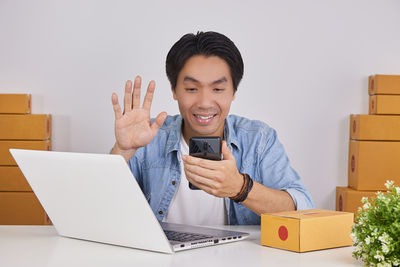 Portrait of smiling young woman using phone on table