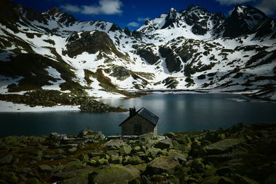 Scenic view of snowcapped mountains, hut and lake against sky