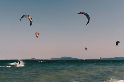 Person paragliding over sea against sky