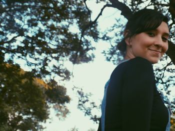 Low angle view of woman standing against trees