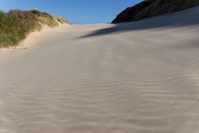 Surface level of sand dunes at beach against sky