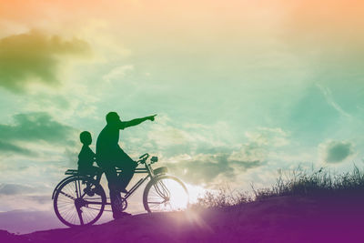 Silhouette person riding bicycle on field against sky during sunset