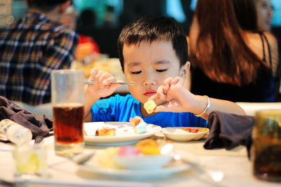 Close-up of cute boy eating food at restaurant
