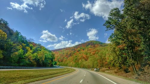 Road by trees against sky