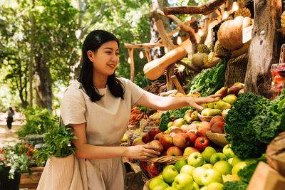 Portrait of young woman holding fruits at market