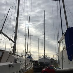 Sailboats against cloudy sky at harbor