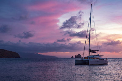 Sailboat sailing on sea against sky during sunset