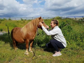 Woman with horse on field against sky