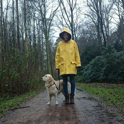 Young woman wearing raincoat standing with dog