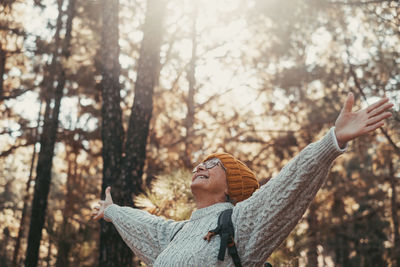 Young woman looking away while standing in forest