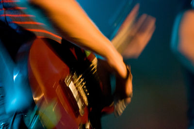 Midsection of man playing guitar at music concert