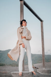 Portrait of young woman standing on land against sky