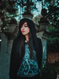 Portrait of a beautiful young woman standing against trees