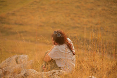 Rear view of woman sitting on field