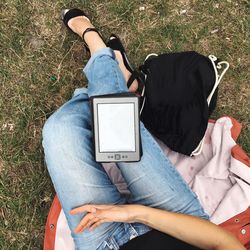 Low section of woman lying on grassy field