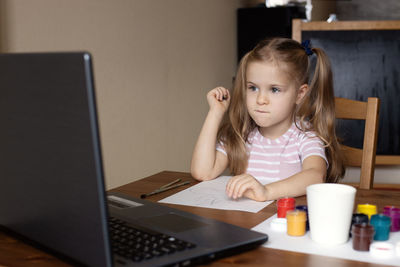 Cute boy using laptop at table