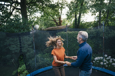 Cheerful man and woman jumping on trampoline