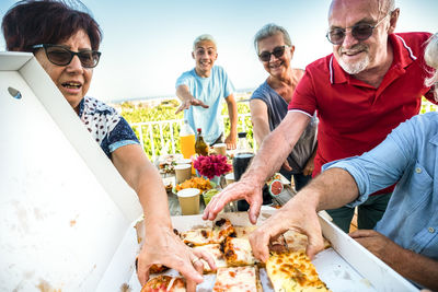 Smiling people holding pizza outdoors