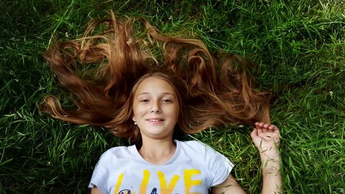 High angle portrait of young woman lying on grassy field