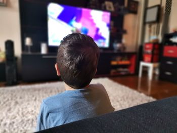 Rear view of boy looking at camera at home