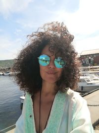 Portrait of woman with tousled curly hair against sky