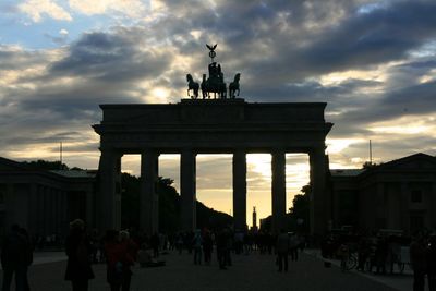 Tourists in front of building against cloudy sky