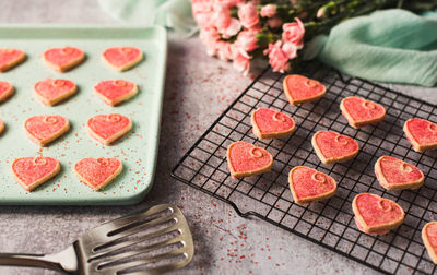 Pink valentine's day heart cookies cooling on a pan and rack.